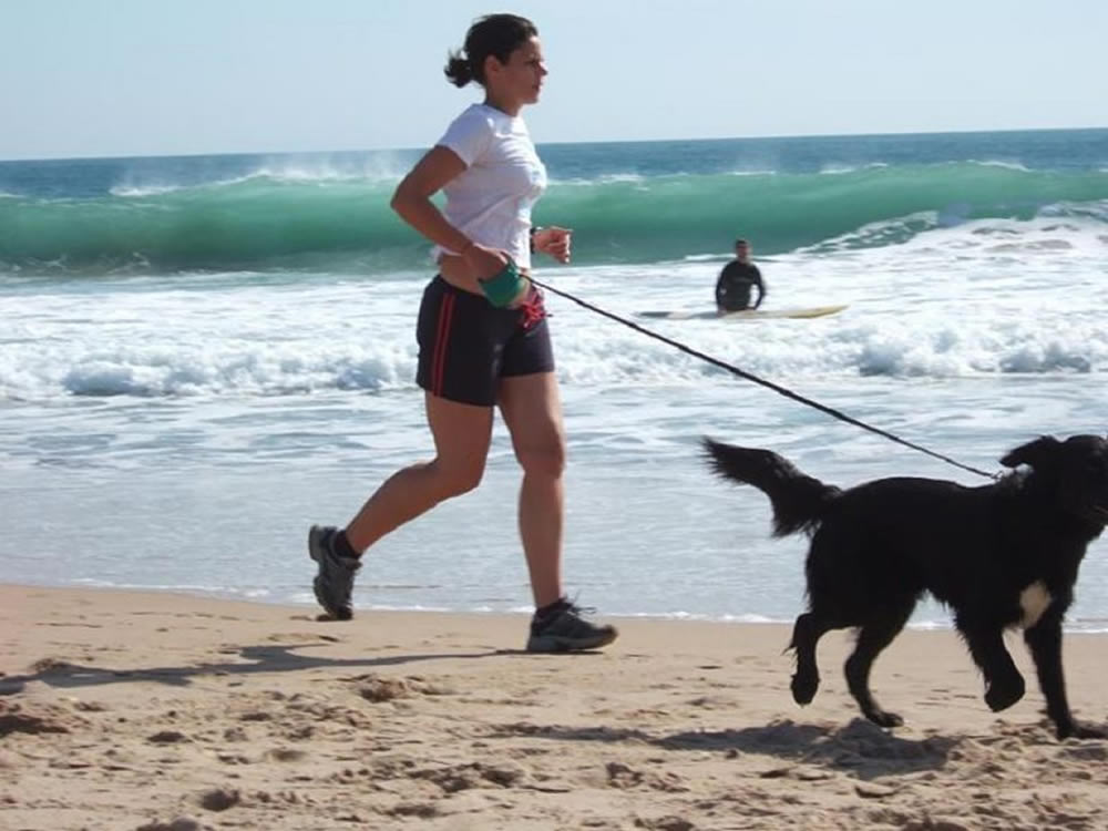 Woman and dog running on beach are healthy because of affordable care act