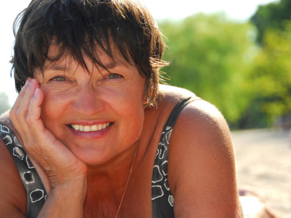 Smiling woman on beach has a happy retirement thanks to roth 401(k) plan