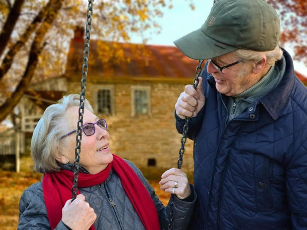 Senior man talks to senior woman on swing about mortgage tips for retirement