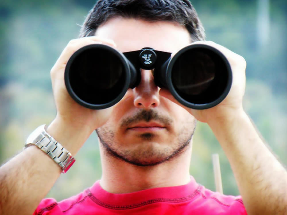 Man with binoculars looks towards a potentially inflationary era ahead