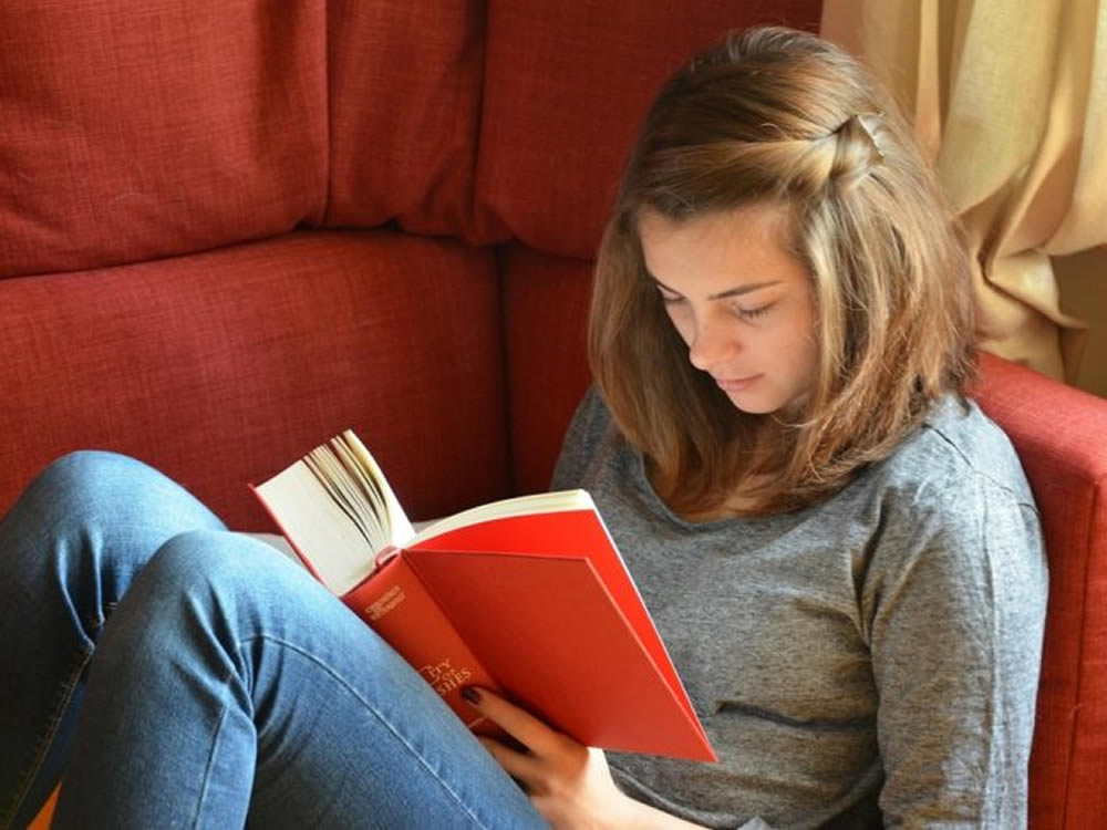 College student reading book on couch is subject to college funding decisions