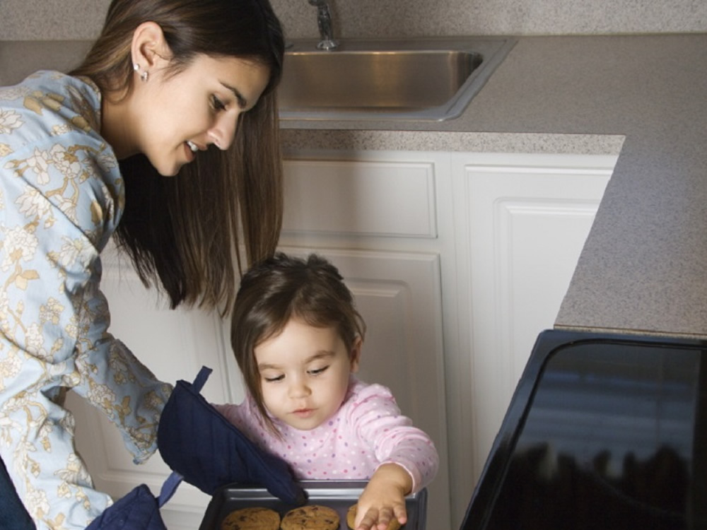 Domestic employee and toddler baking cookies together