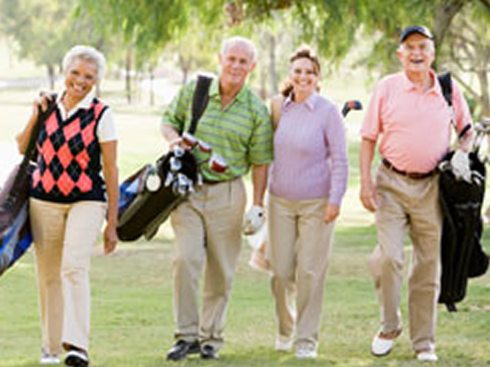 Two couples enjoy golfing after choosing a retirement community