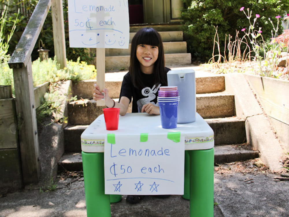 Girl running lemonade stand helps kids learn to save money