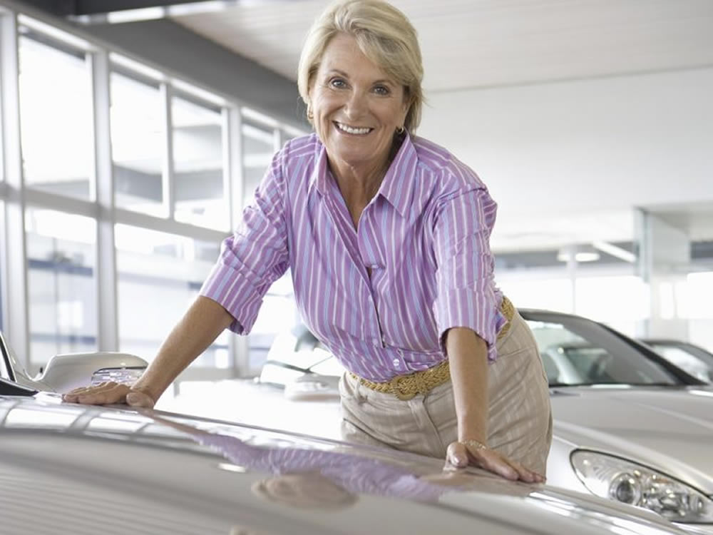 Woman retiree considers how to spend her pension option payout in new car salesroom