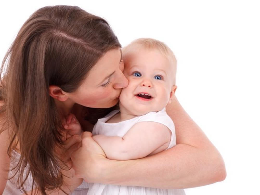 Young mother kissing baby, aware of the importance of life insurance for women