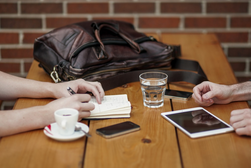 Man and woman talk at coffee table about the most common financial scams and how to avoid them