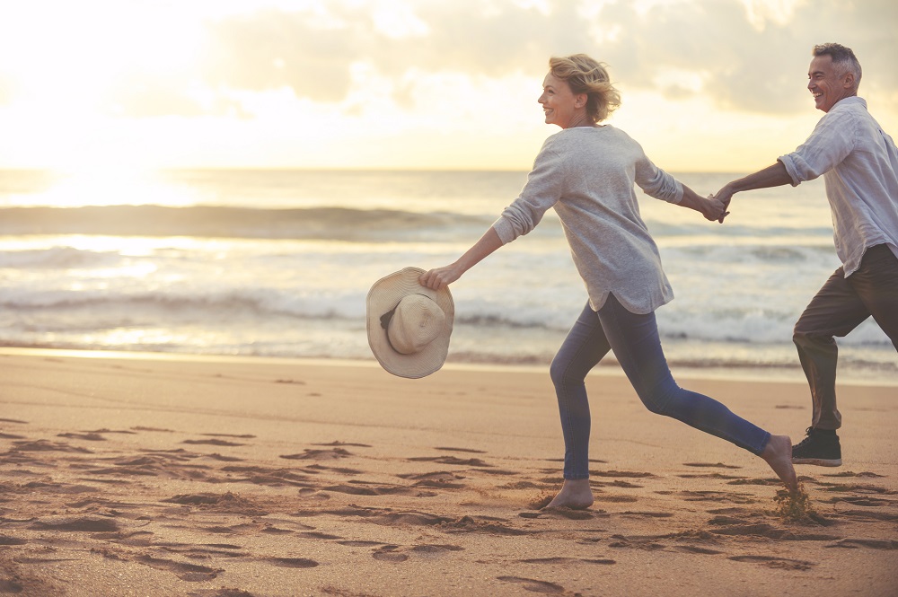 Happy couple running on beach have planned for how long you'll live in retirement