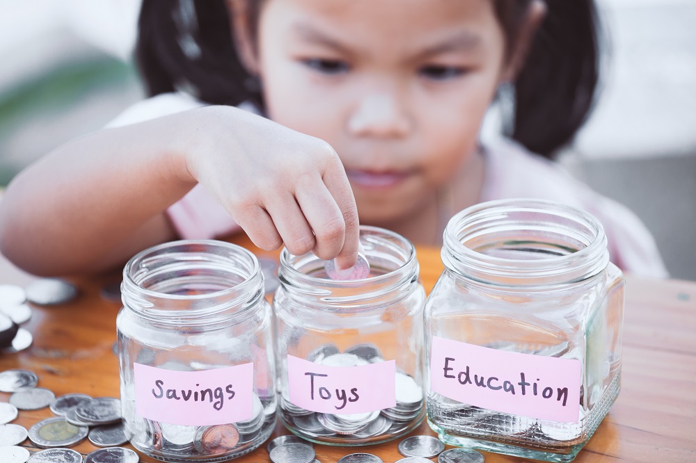 Little girl understands that saving and spending milestones for kids help with financial learning